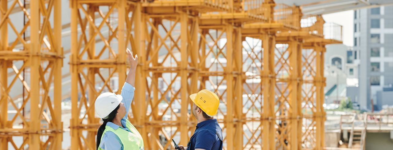 Two workers in hard hats reviewing work at a framed structure